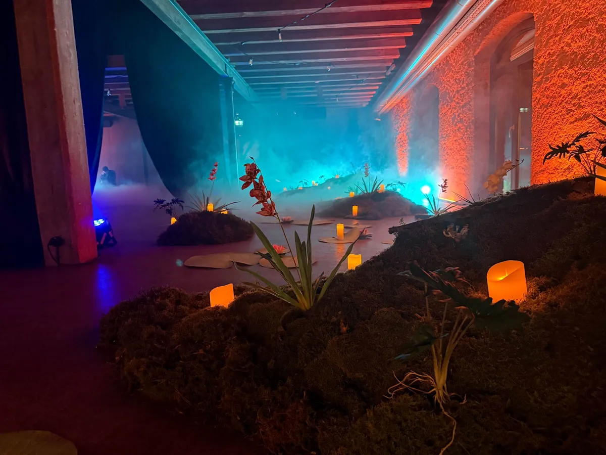 Vorraum der Masquerade Party: Moosinseln, Kerzen und Nebel im türkis und orange beleuchteten Gewölbe
